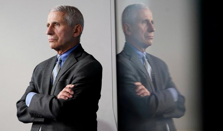 FILE PHOTO: National Institute of Allergy and Infectious Diseases Director Dr. Anthony Fauci is reflected in a video monitor behind him on stage as he listens to the daily coronavirus task force briefing at the White House in Washington, U.S., April 8, 20