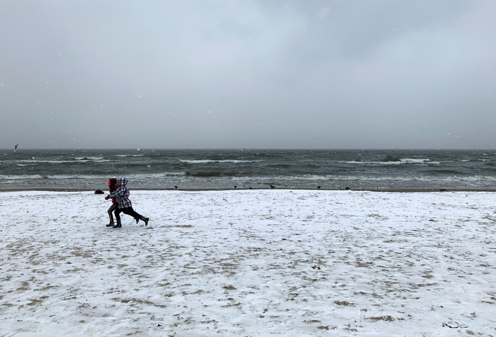 Children run on the beach during a snowfall in Sopot, Poland January 15, 2021. REUTERS/Radu Sigheti