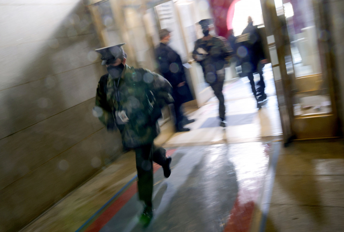 A member of the military rushes past, as people are evacuated back inside after an 