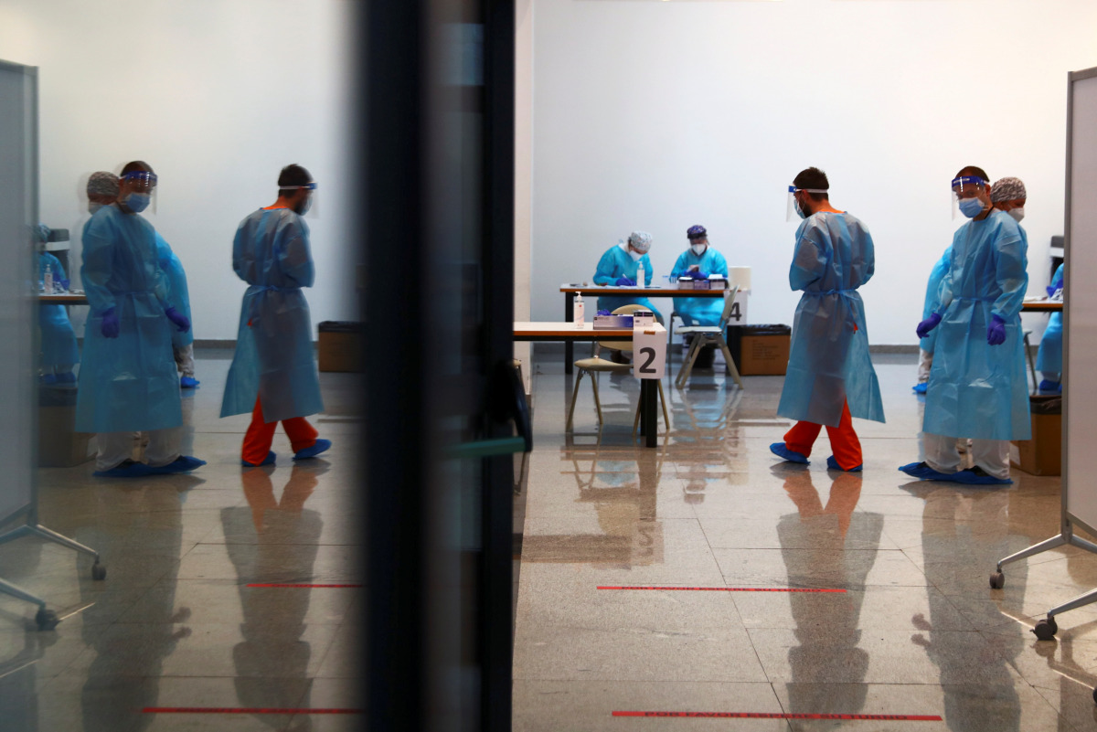 Health workers stand as they wait to take swab samples from young people for a coronavirus disease (COVID-19) antigen test at Rey Juan Carlos University in Mostoles, Spain, January 20, 2021. REUTERS/Sergio Perez
