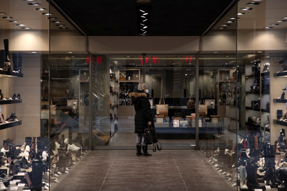 A woman wearing a protective face mask waits to enter a shop on the first day of the re-opening of retail stores, amid the coronavirus disease (COVID-19) pandemic, in Athens, Greece, January 18, 2021. REUTERS/Alkis Konstantinidis