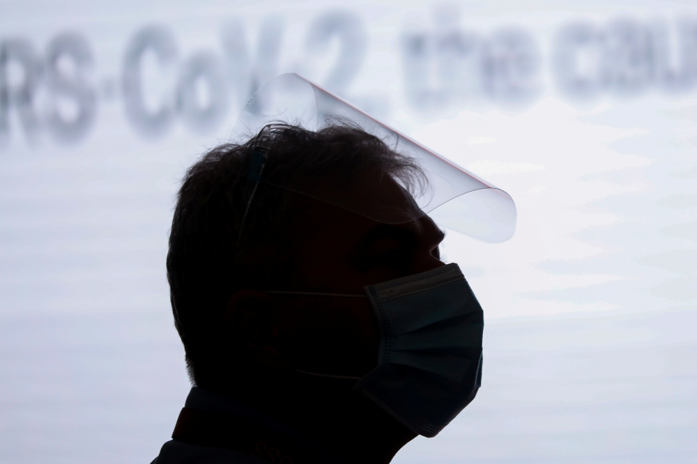 A man wearing a face mask and face shield is silhouetted during a press briefing at Philippine Red Cross in Mandaluyong City, Metro Manila, Philippines, January 25, 2021. REUTERS/Eloisa Lopez