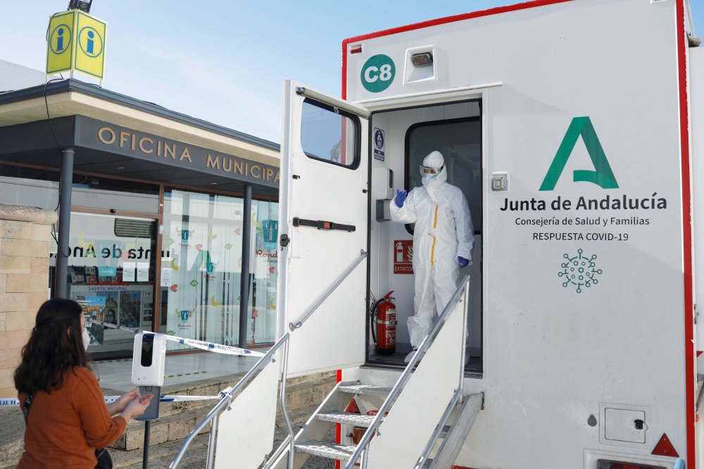 A healthcare worker gestures to a woman to be tested for the coronavirus disease (COVID-19) during massive testing in a mobile laboratory truck in Ronda, southern Spain January 29, 2021. REUTERS/Jon Nazca