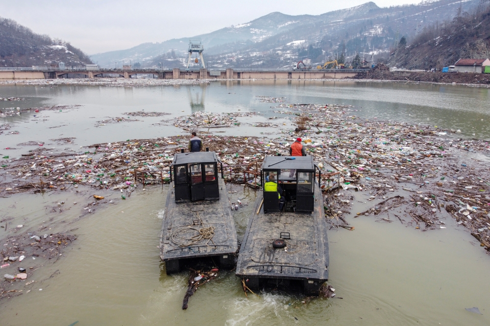 Workers collect plastic trash that litters the polluted Potpecko Lake near a dam's hydroelectric plant near the town of Priboj, Serbia, January 29, 2021. Picture taken with a drone. REUTERS/Marko Djurica