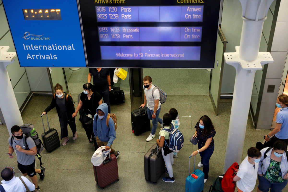 FILE PHOTO: Passengers wearing protective face masks arrive from Paris at Eurostar terminal at St Pancras station, as Britain imposes a 14-day quarantine on arrival from France from Saturday, following the outbreak of the coronavirus disease (COVID-19), i