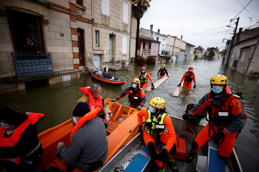 Rescue workers on small boats help residents in a flooded area as the Charente River overflows in Saintes after days of rainy weather causing flooding in western France, France, February 8, 2021. REUTERS/Stephane Mahe