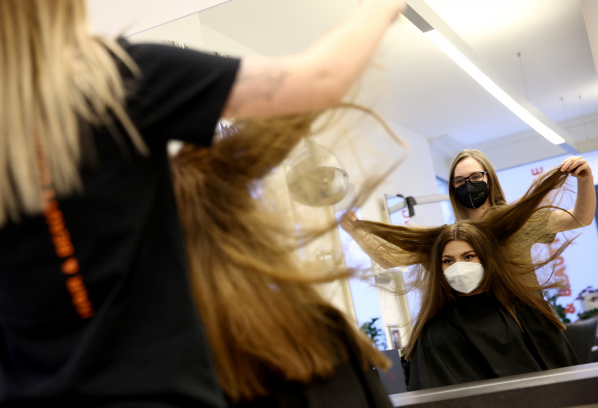Hairdresser Jessica finishes the haircut of a customer after third national lockdown was loosened during the coronavirus disease (COVID-19) continues in Vienna, Austria February 8, 2021. REUTERS/Lisi Niesner
