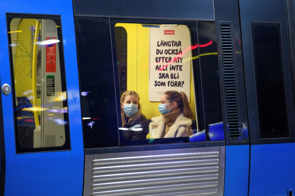 Passengers wearing protective masks sit onboard an underground train, amid the spread of the coronavirus disease (COVID-19) pandemic, in Stockholm, Sweden, January 7, 2021. Jessica Gow/TT News Agency/via REUTERS