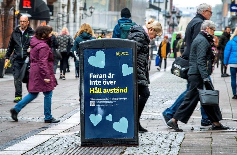 FILE PHOTO: People walk near a trash can with a sign reading 