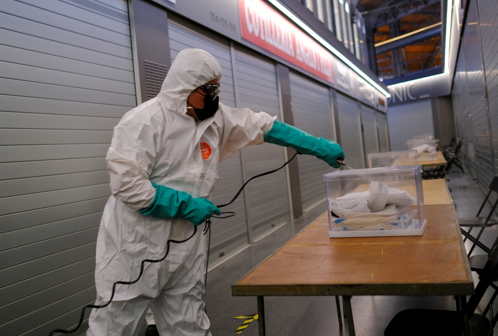 A worker uses disinfectant to clean ballot boxes containing personal protective equipment (PPE) supplies at Sant Antoni Market, which will be a polling station for the February 14th regional election, during the coronavirus disease (COVID-19) outbreak in 