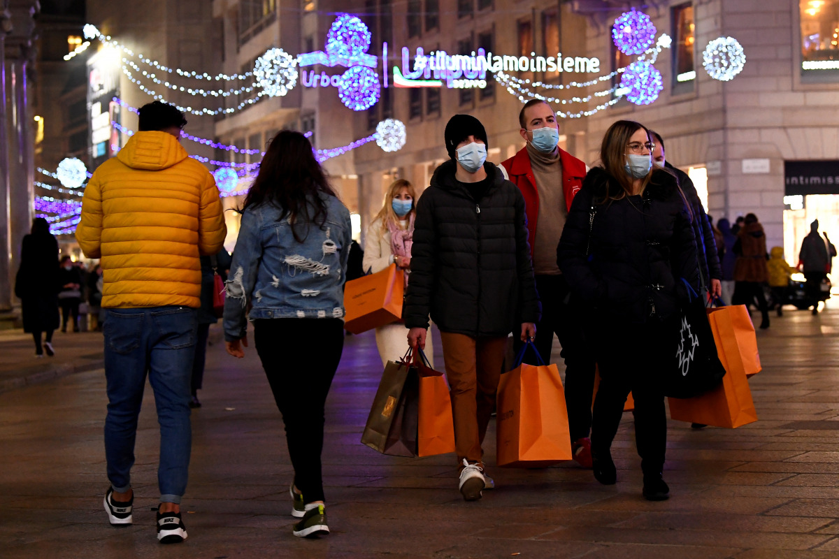 FILE PHOTO: People wearing protective face masks walk along a shopping street as the government prepares to bring in further restrictions over the Christmas period to curb the spread of the coronavirus disease (COVID-19) in Milan, Italy, December 18, 2020