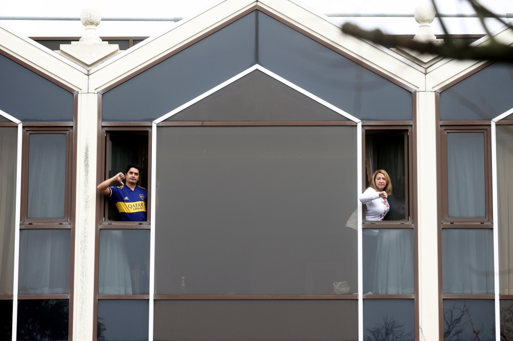 People gesture from windows at the Radisson Blu Hotel at Heathrow Airport, as Britain introduces a hotel quarantine programme for arrivals from a 