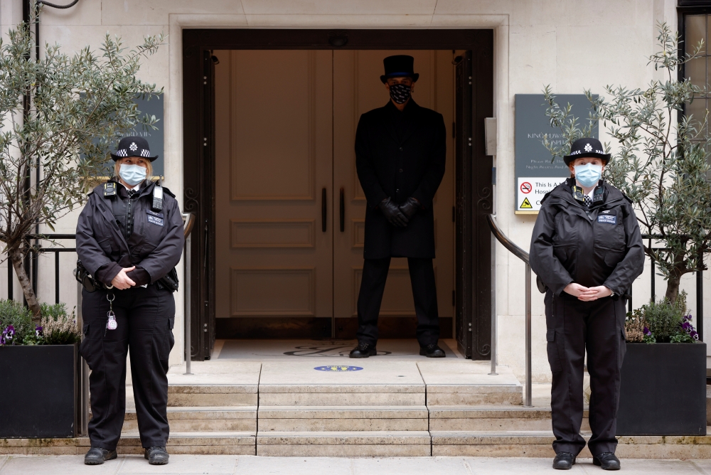 Police officers and a doorman stand outside King Edward VII's Hospital, where Britain's Prince Philip was admitted, in London, Britain March 5, 2021. REUTERS/John Sibley