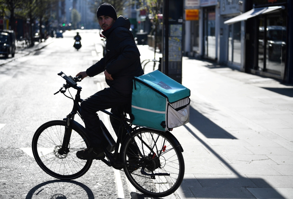 A courier for food delivery service Deliveroo rides a bike, as as the spread of the coronavirus disease (COVID-19) continues, in London, Britain, March 24, 2020. REUTERS/Dylan Martinez/File Photo