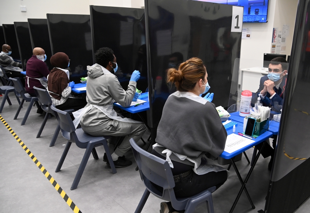 Health workers and volunteers assist as students take coronavirus disease (COVID-19) tests at Harris Academy Beckenham, ahead of full school reopening in England as part of lockdown restrictions being eased, in Beckenham, south east London, Britain, March