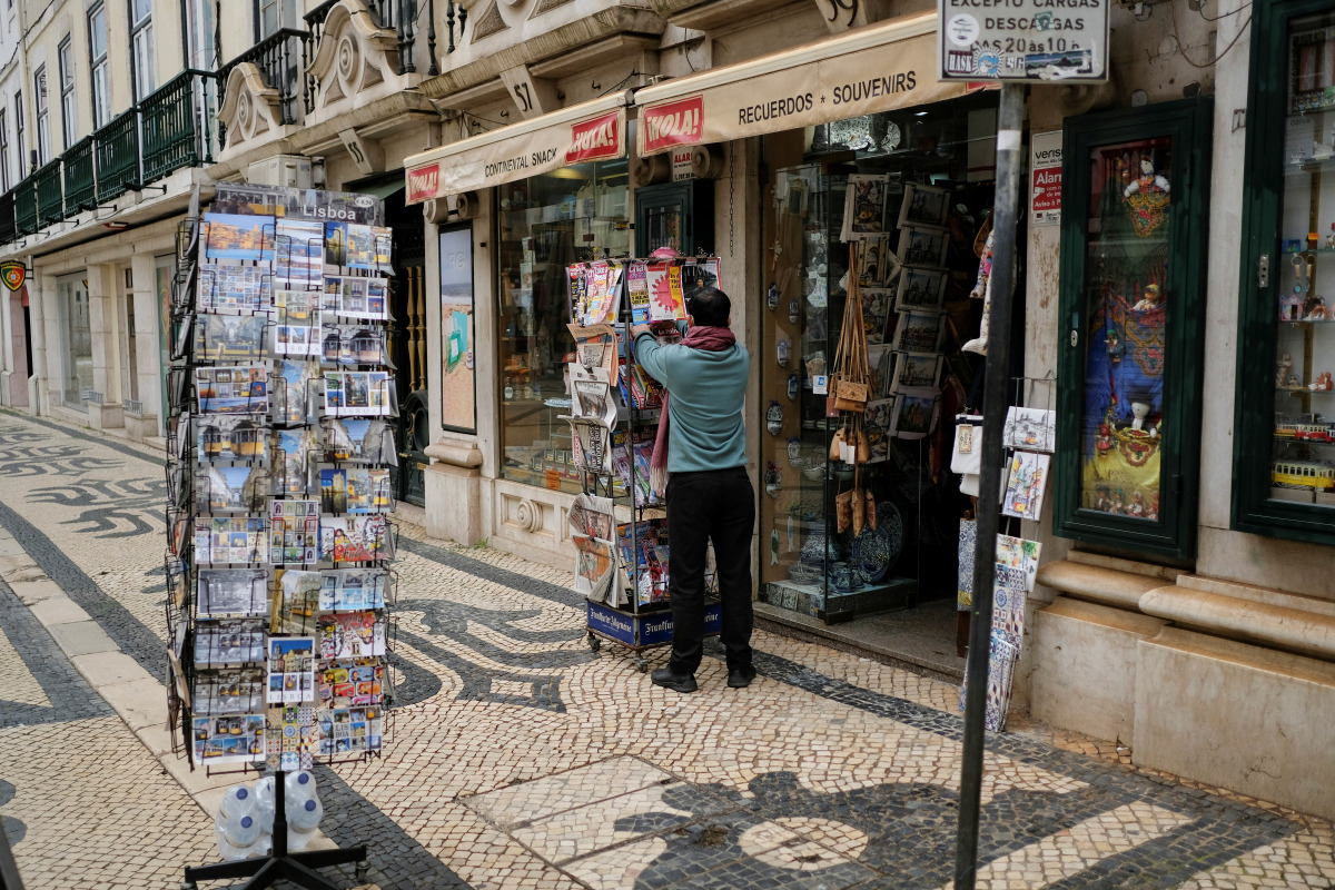 A man organizes newspapers in front of a store in Lisbon downtown amid the coronavirus disease (COVID-19) pandemic, in Lisbon, Portugal, March 11, 2021. REUTERS/Pedro Nunes
