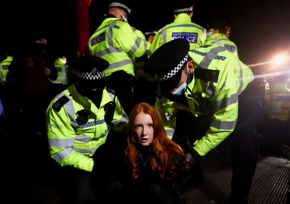 Police detain a woman as people gather at a memorial site in Clapham Common Bandstand, following the kidnap and murder of Sarah Everard, in London, Britain March 13, 2021. Reuters/Hannah McKay