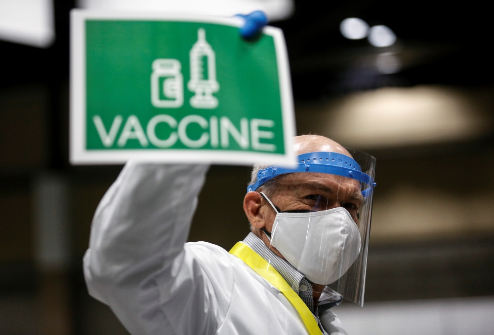 Doctor John Thayer holds up a sign to signal his station needs more vaccine doses as people attend a coronavirus disease (COVID-19) vaccination site at Lumen Field Event Center in Seattle, Washington, U.S. March 13, 2021. Reuters/Lindsey Wasson