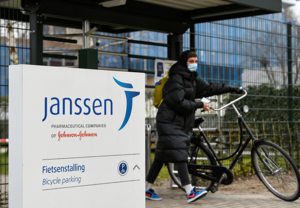 A woman leaves with her bike at Johnson and Johnson's subsidiary Janssen Vaccines in Leiden, Netherlands March 9, 2021. REUTERS/Piroschka van de Wouw/File Photo