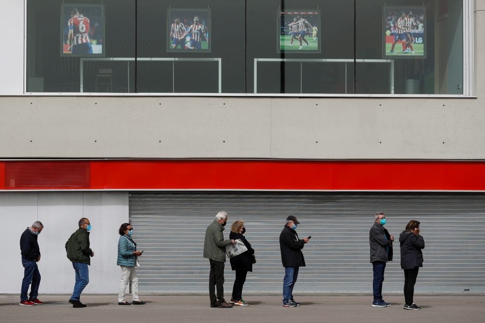 People wait in line to receive a dose of AstraZeneca's COVID-19 vaccine outside a vaccination centre, at the Wanda Metropolitano stadium, in Madrid, Spain, March 31, 2021. REUTERS/Susana Vera