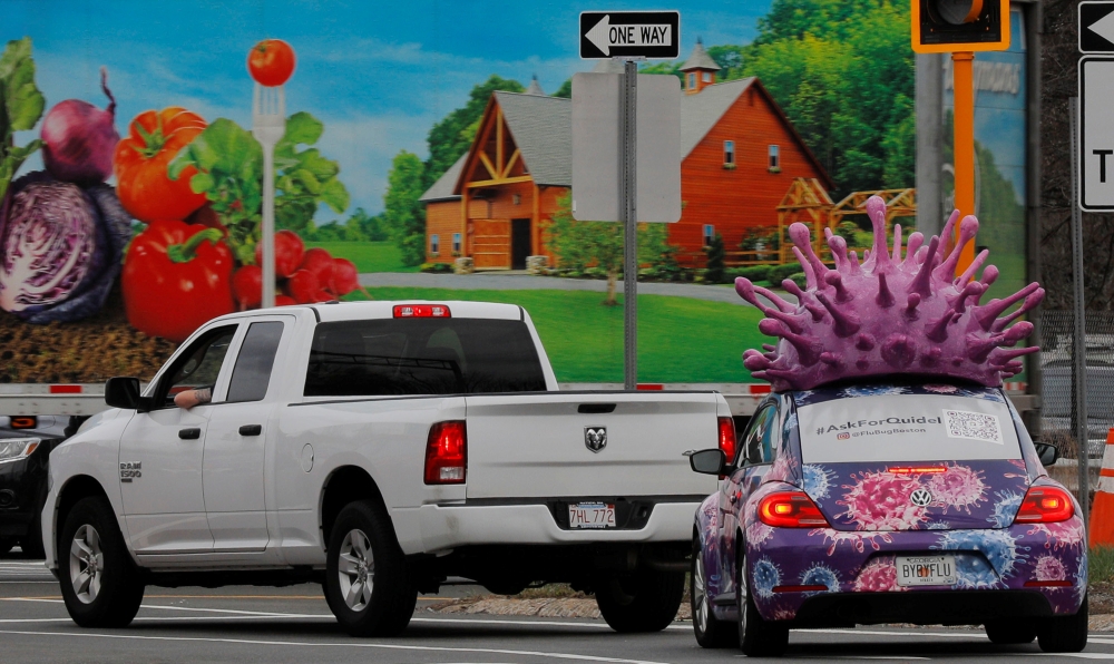 A car, advertising for a company that makes test kits for both the flu and the coronavirus disease (COVID-19) waits at a traffic light with a large model of the influenza virus on its roof, in Medford, Massachusetts, U.S., March 31, 2021. REUTERS/Brian Sn