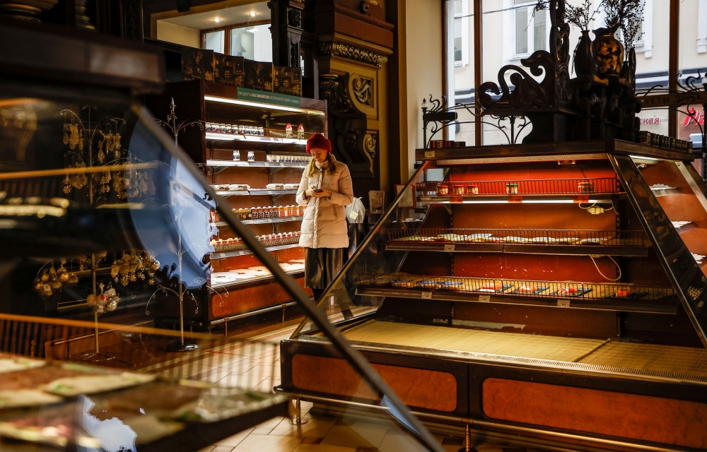A woman uses a smartphone at Yeliseyevsky Store in central Moscow, Russia April 2, 2021. A historic grocery store in central Moscow is to close its doors after trading for more than a hundred years due to legal issues and a drop in tourism caused by the C