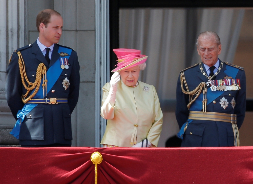 Britain's Queen Elizabeth waves as she stands with Prince William (L) and Prince Philip as they prepare to view a RAF flypast to mark the 75th anniversary of the Battle of Britain, from the balcony of Buckingham Palace in London, Britain July 10, 2015. RE