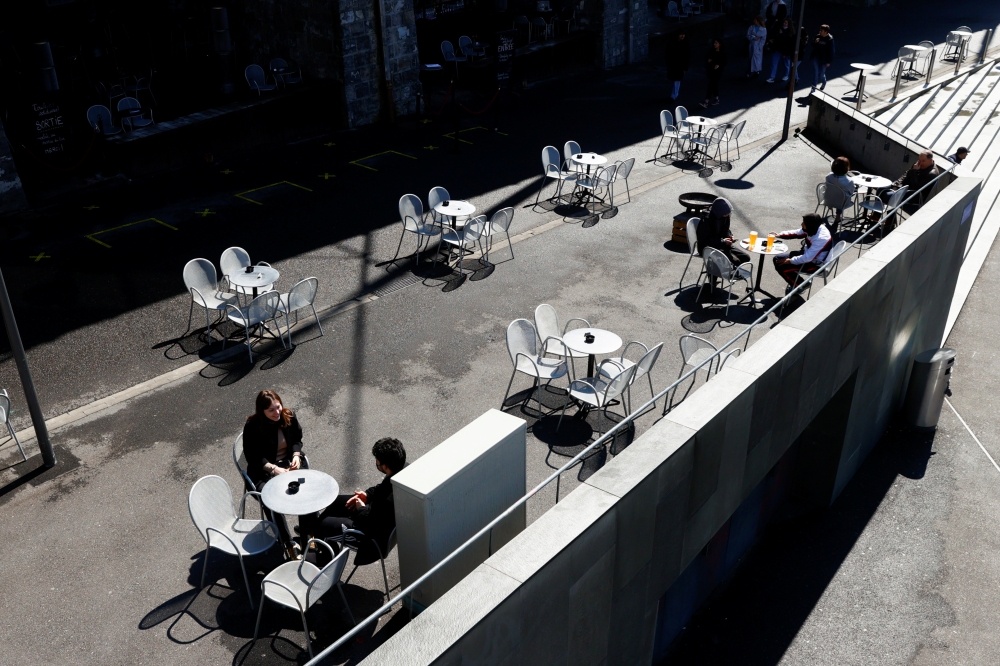 People sit on a terrace at Les Arches bar in the city centre, as coronavirus disease (COVID-19) lockdown restrictions ease, in Lausanne, Switzerland April 19, 2021. REUTERS/Denis Balibouse