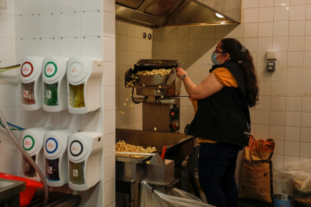 A woman prepares popcorn for takeaway on the first day of the opening of cinema theatres after a country lockdown, amid the coronavirus disease (COVID-19) pandemic, in Sintra, Portugal, April 19, 2021. REUTERS/Pedro Nunes