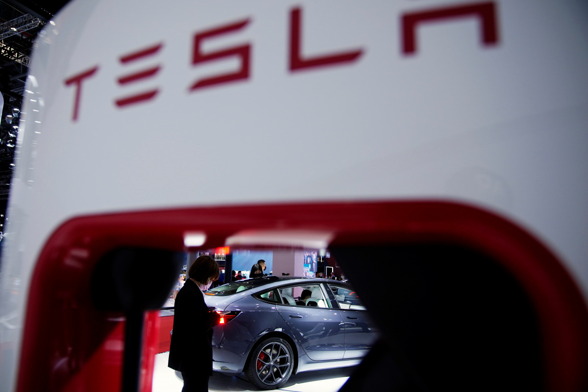 A Tesla electric vehicle (EV) is seen through a charging point displayed during a media day for the Auto Shanghai show in Shanghai, China April 20, 2021. REUTERS/Aly Song
