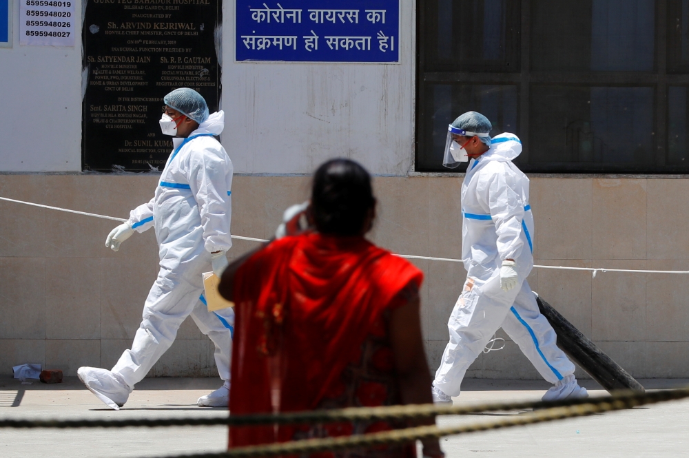 A health worker wearing personal protective equipment (PPE) carries an oxygen cylinder into the casualty ward at Guru Teg Bahadur Hospital, in New Delhi, India, April 24, 2021. REUTERS/Adnan Abidi
