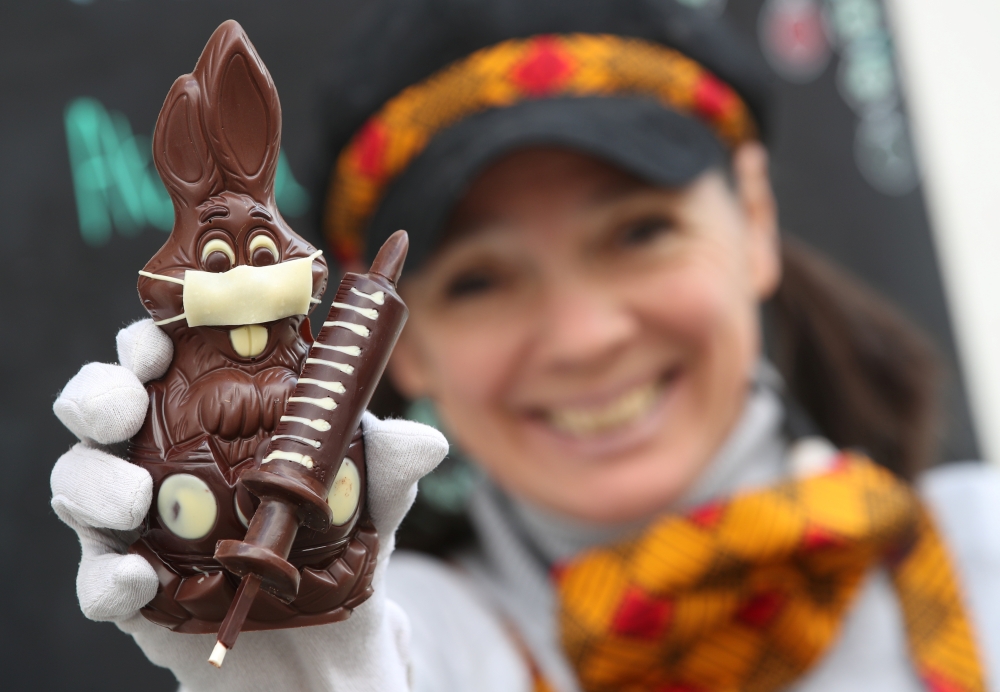 Belgian artisan chocolate maker Genevieve Trepant shows a chocolate bunny wearing a protective mask and holding a vaccine syringe called 