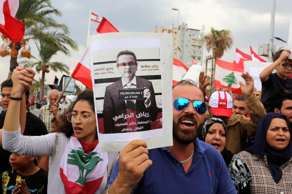 File photo: Demonstrators carry Lebanese flags and a banner depicting Lebanon's Central Bank Governor Riad Salameh, as they head towards the central bank building during an anti-government protest in the southern city of Tyre, Lebanon October 23, 2019. Re