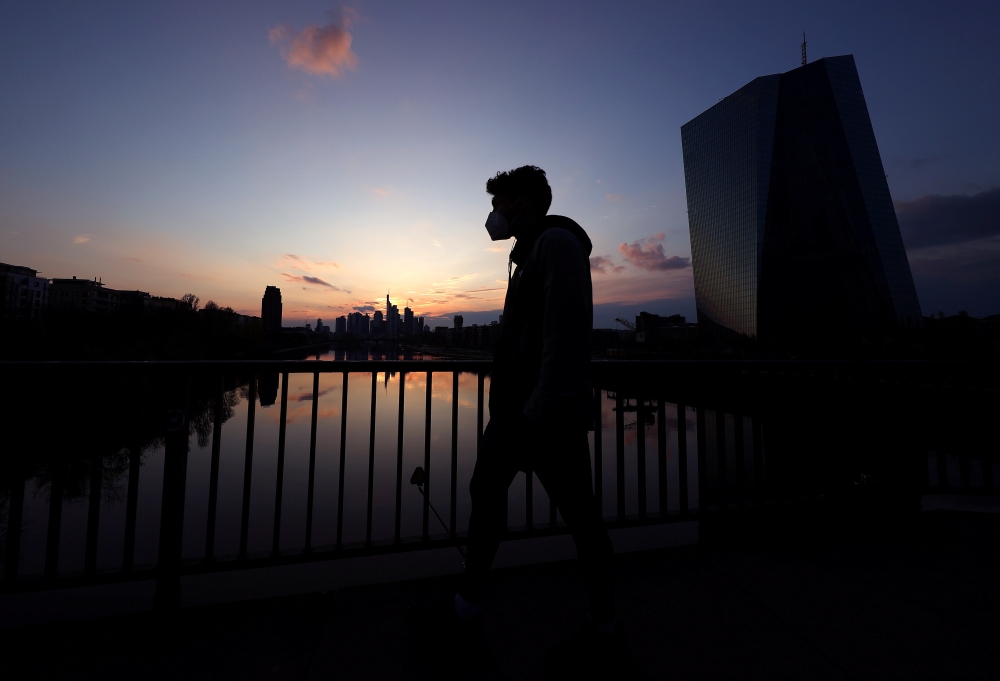  A man wearing a protective mask walks past the European Central Bank (ECB) during sunset as the spread of the coronavirus disease (COVID-19) continues in Frankfurt, Germany, April 18, 2021. REUTERS/Kai Pfaffenbach/File Photo