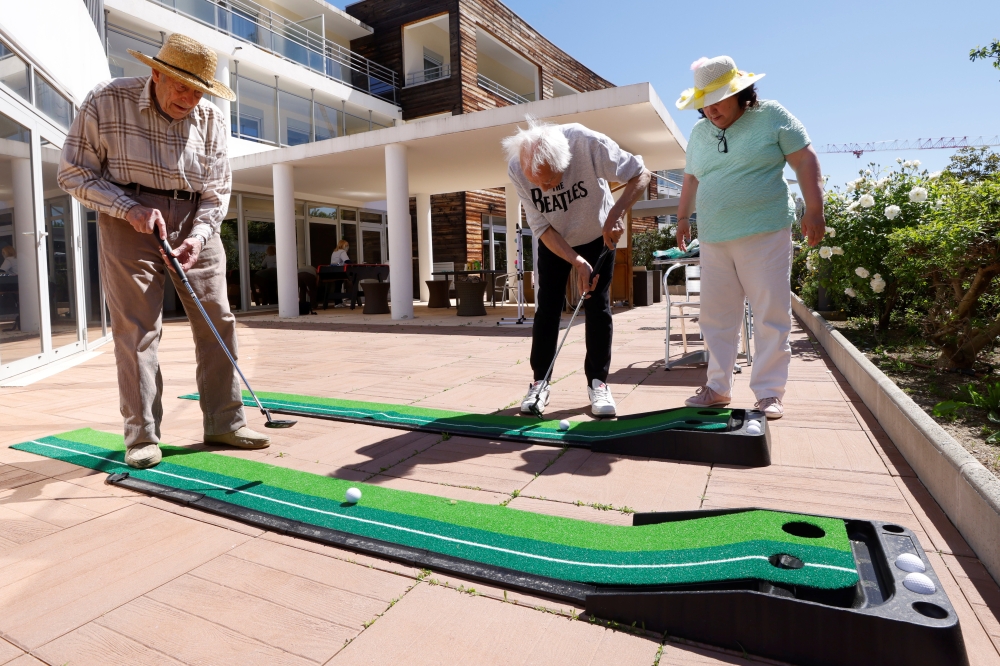Residents Paul Souveton, Bernard Sellier and Frederique Benichou play mini golf at 