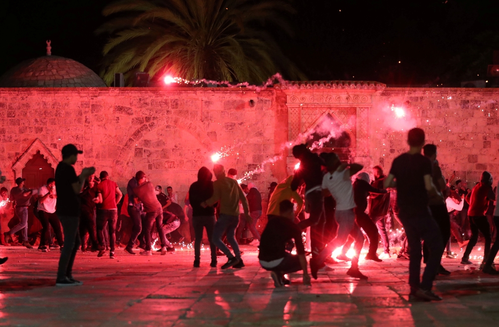 Palestinians react as Israeli police fire stun grenades during clashes at the compound that houses Al-Aqsa Mosque in Jerusalem on May 7, 2021. (REUTERS/Ammar Awad)
