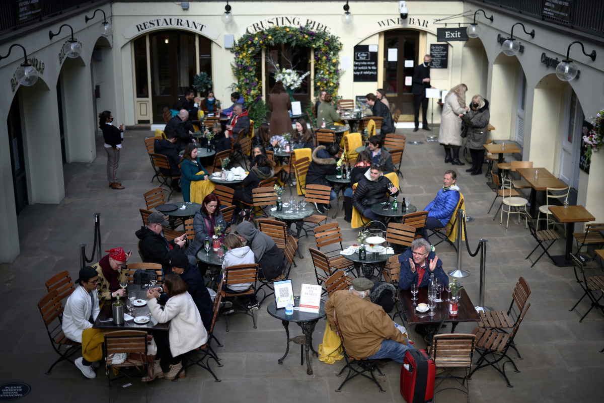 FILE PHOTO: People sit at outside restaurant area, as the coronavirus disease (COVID-19) restrictions ease, at Covent Garden in London, Britain April 12, 2021. REUTERS/Henry Nicholls/File Photo
