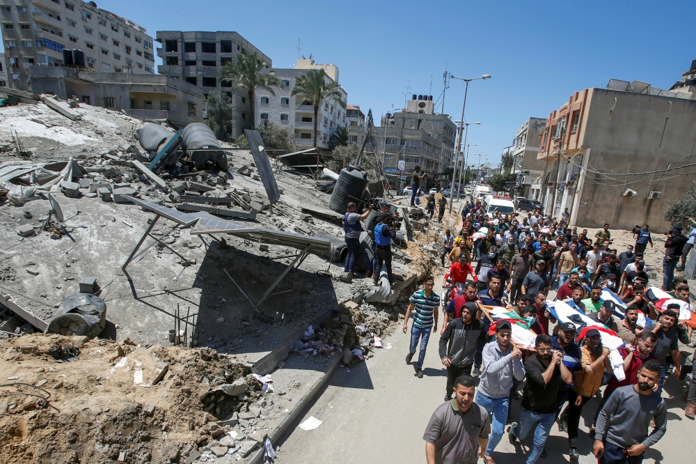 Mourners carry the bodies of Palestinians, including members of Abu Hatab family, who were killed amid a flare-up of Israeli-Palestinian violence, during their funeral near the remains of a building destroyed in Israeli air strikes, at the Beach refugee c