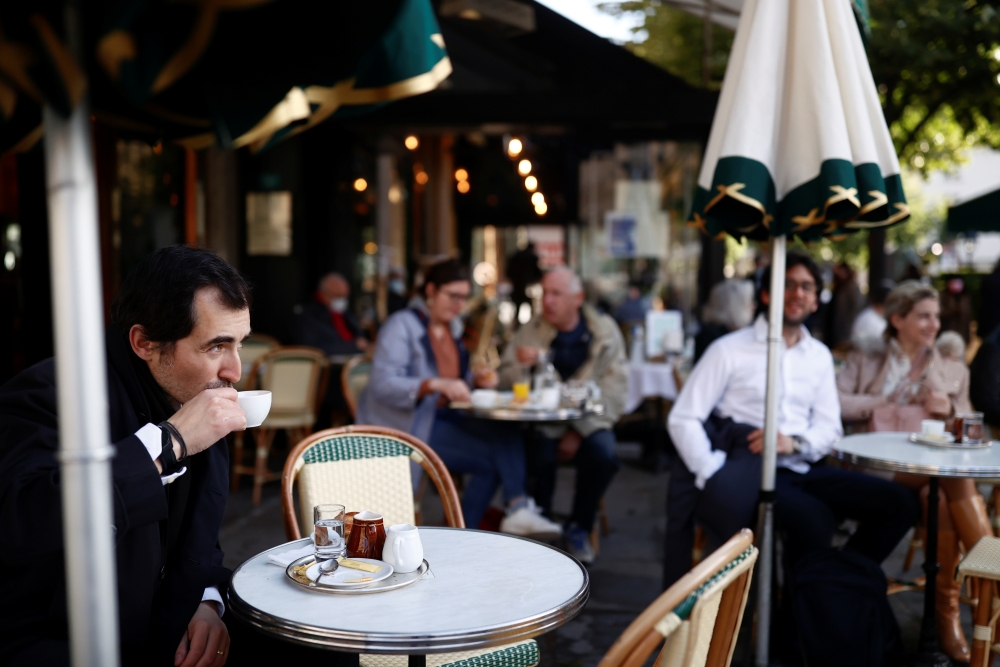 A customer enjoys a drink at the terrace of the cafe and restaurant Les Deux Magots, as cafes, bars and restaurants reopen their terraces after closing down for months, amid the coronavirus disease (COVID-19) outbreak, in Paris, France, May 19, 2021. Reut