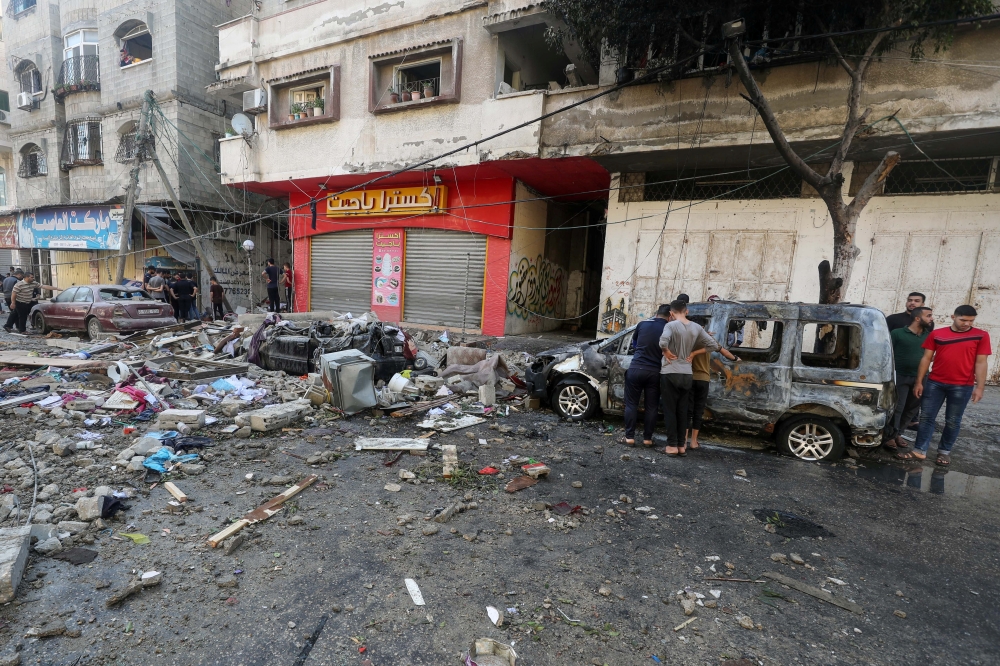 Palestinians inspect a damaged vehicle in the aftermath of an Israeli airstrike on a house in Gaza City, May 19, 2021. Reuters/Mohammed Salem