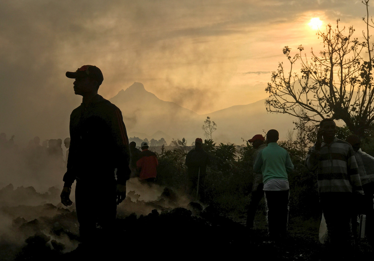 Residents walk near destroyed homes with the smouldering lava deposited by the eruption of Mount Nyiragongo volcano near Goma, in the Democratic Republic of Congo May 23, 2021. REUTERS/Djaffar Al Katanty 