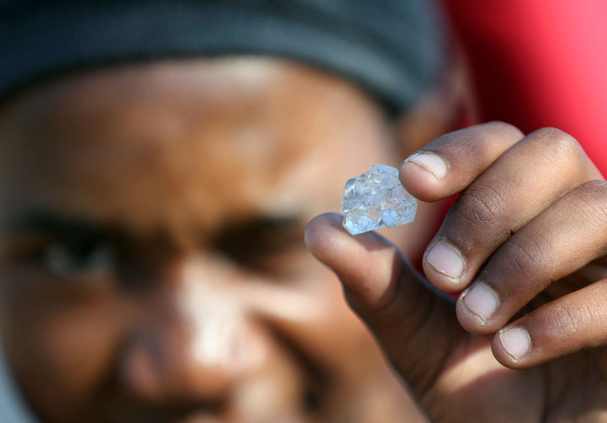 A man shows an unidentified stone as fortune seekers flock to the village after pictures and videos were shared on social media showing people celebrating after finding what they believe to be diamonds, in the village of KWAHLATHI outside Ladysmith, in Kw