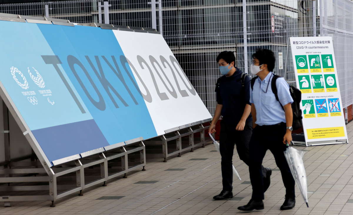 People walk past a sign advertising the 2020 Tokyo Olympic Games that have been postponed to 2021 due to the coronavirus disease (COVID-19) pandemic during the opening of the IBC/MPC media center at Tokyo Big Sight exhibition center in Tokyo, Japan July 1