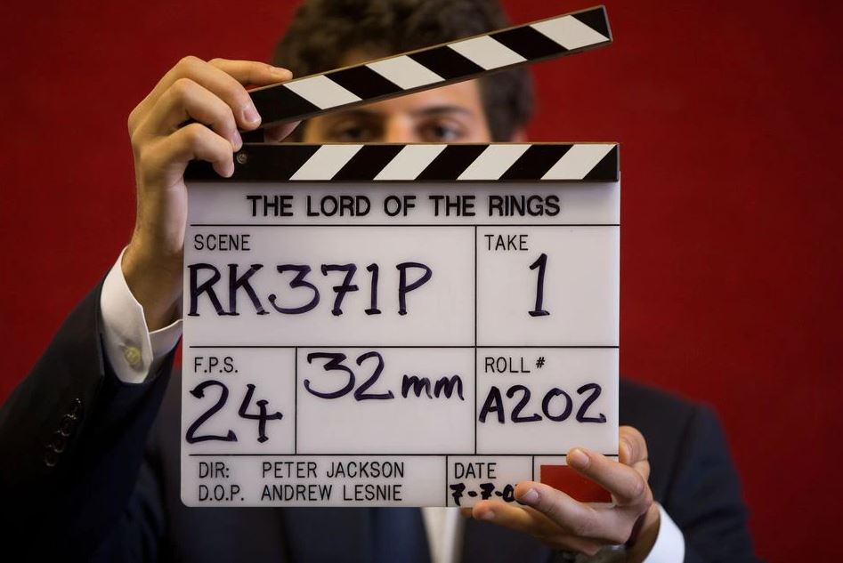 A gallery assistant poses for a photograph with a clapper board used in the filming of the Lord of the Rings film 'Return of the King' in Bonhams auction house in London July 31, 2014. REUTERS/Neil Hall