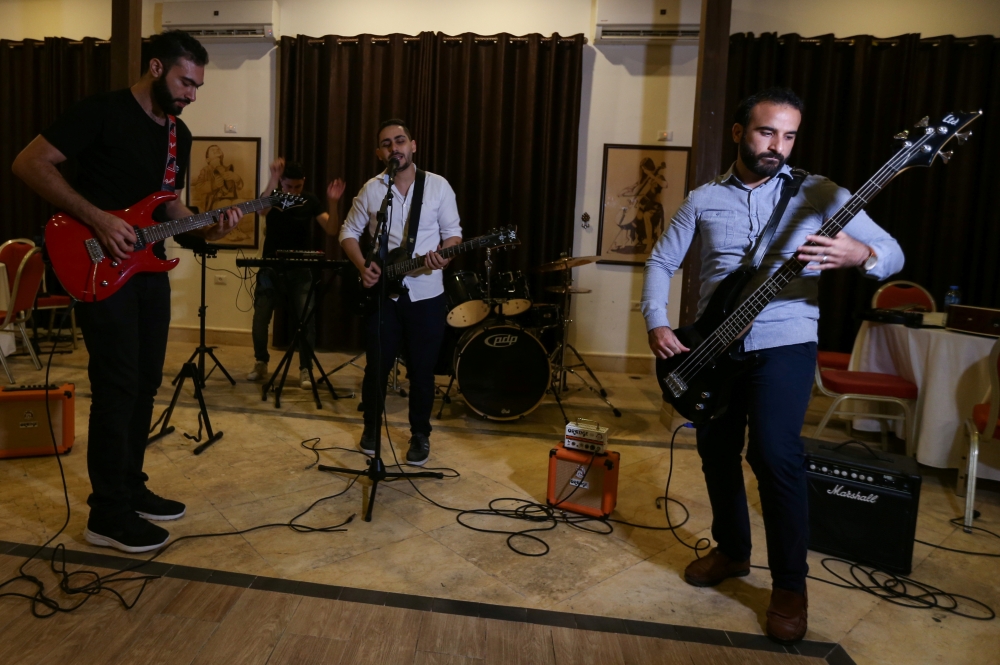 Palestinian accountant Raji El-Jaru and his two cousins, lawyers Saed and Moamin El-Jaru, sing and play the guitar during a rehearsal for the first rock music band Osprey V in Gaza City on August 1, 2021. Reuters/Ibraheem Abu Mustafa