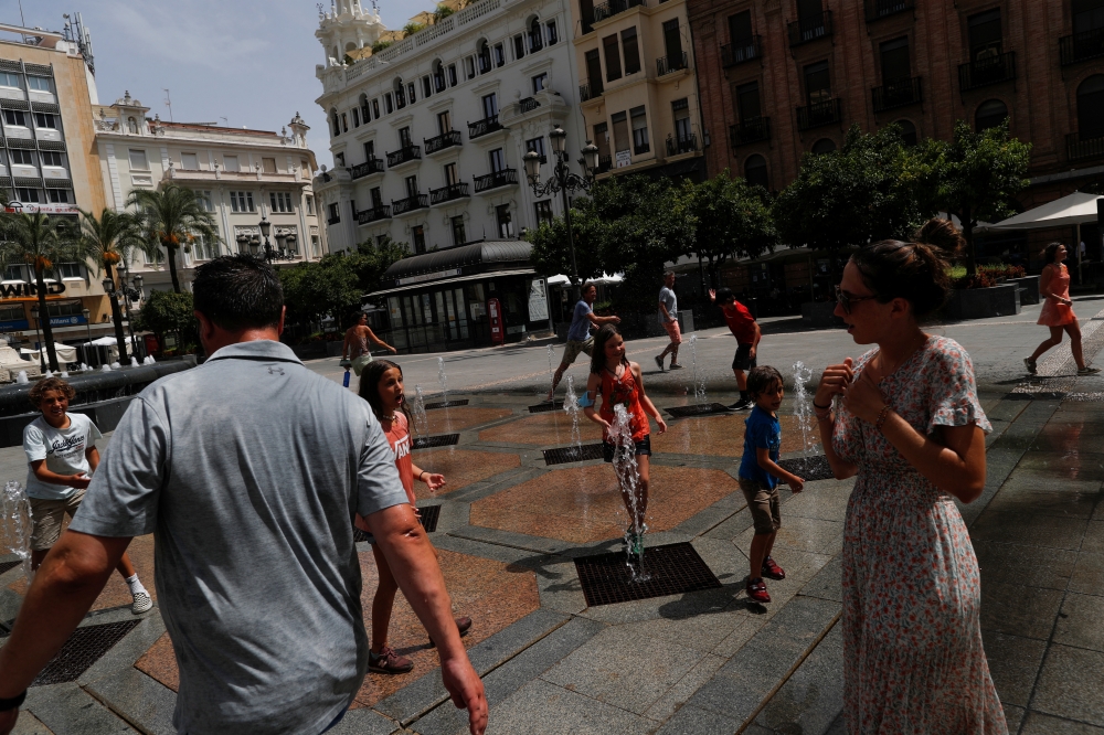 Three french tourist families cool off in a fountain at the Las Tendillas square, as a heatwave hits Spain, in Cordoba, southern Spain, August 14, 2021. REUTERS/Jon Nazca