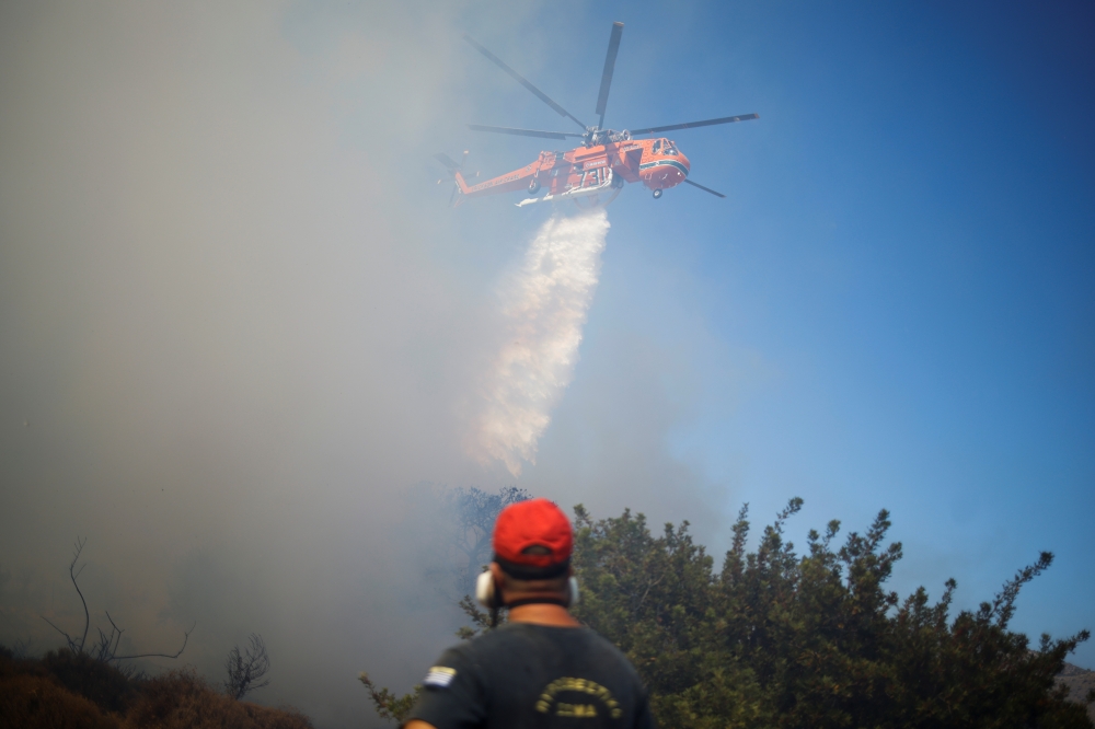 A firefighting helicopter makes a water drop as a wildfire burns in the village of Markati, near Athens, Greece, August 16, 2021. REUTERS/Alkis Konstantinidis