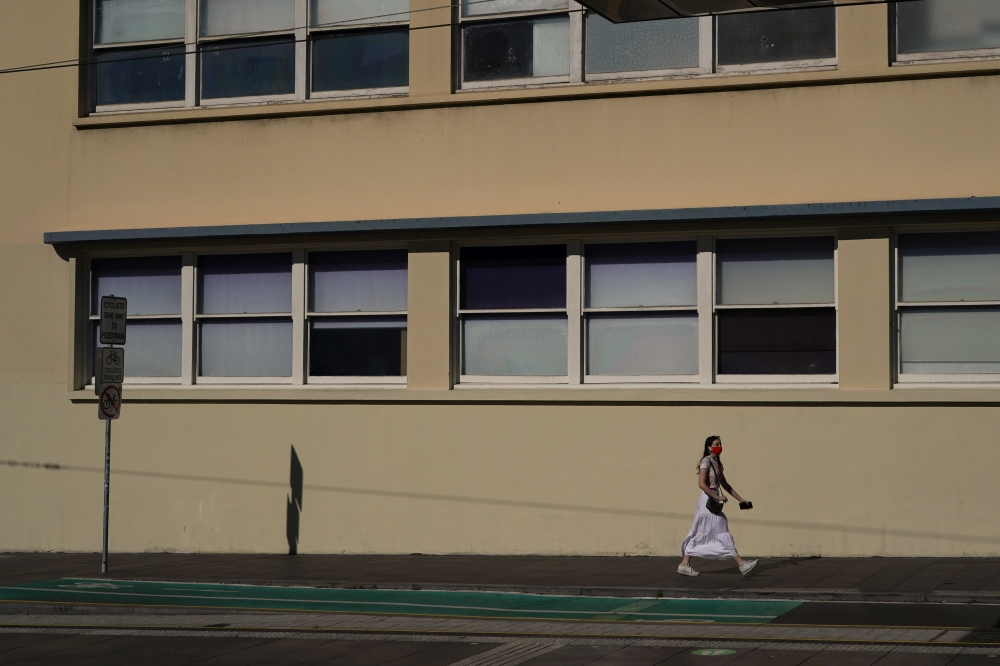 A lone pedestrian wears a face mask while walking through the city centre during a lockdown to curb the spread of an outbreak of the coronavirus disease (COVID-19) in Sydney, Australia, August 17, 2021. REUTERS/Loren Elliott