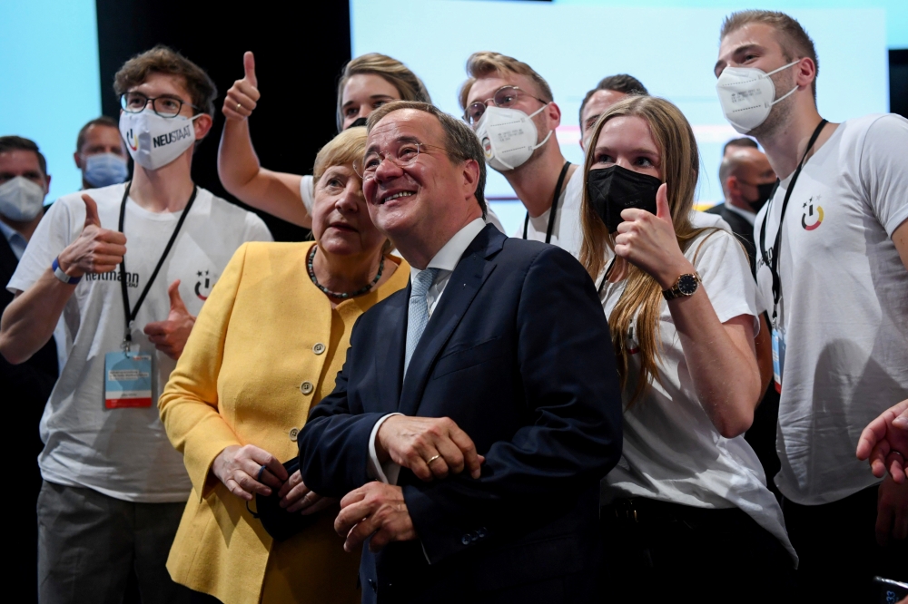 Prime Minister of North Rhine-Westphalia and candidate for chancellor of the CDU/CSU Armin Laschet and German Chancellor Angela Merkel pose for a selfie with participants during a CDU/CSU campaign kick off ahead of the federal election at Tempodrom in Ber