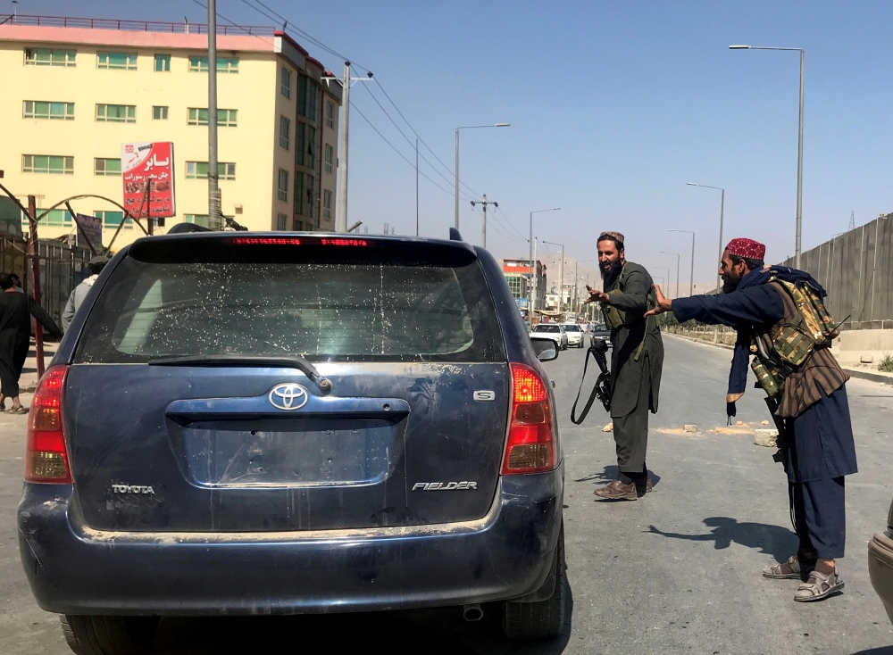 FILE PHOTO: Members of Taliban forces gesture as they check a vehicle on a street in Kabul, Afghanistan, August 16, 2021. REUTERS